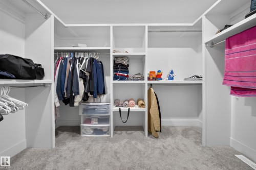 Built-in white shelving and hanging rods, integrated overhead shelving, plush carpet flooring, and recessed lighting - 3217 Pelerin Crescent, Beaumont, AB - Indoor With Storage