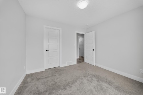 Light gray wall paint, white trim, paneled white doors, dark door hardware, and gray carpet flooring - 3217 Pelerin Crescent, Beaumont, AB - Indoor Photo Showing Other Room
