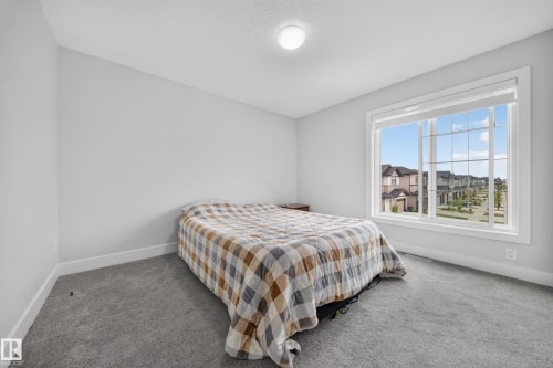 Wall-to-wall carpeting, large window with grid pattern, neutral wall paint, and overhead flush-mount lighting fixture - 3217 Pelerin Crescent, Beaumont, AB - Indoor Photo Showing Bedroom
