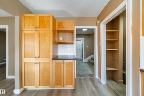 Wood-finish flooring with light wood cabinetry, dark countertop, and white tile backsplash - 115 Griesbach Road Nw, Edmonton, AB - Indoor