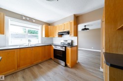 Wood-finish cabinetry, stainless steel range, white subway tile backsplash, dark countertops, and wood-finish flooring - 