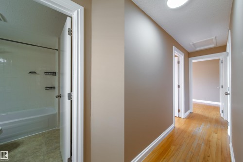 Hallway featuring wood-finish flooring, neutral wall paint, and white trim - 115 Griesbach Road Nw, Edmonton, AB - Indoor Photo Showing Other Room