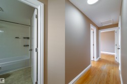 Hallway featuring wood-finish flooring, neutral wall paint, and white trim - 