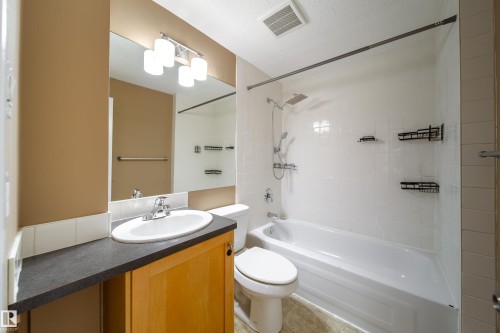 Vanity with wood-finish cabinetry, dark countertop, and integrated sink - 115 Griesbach Road Nw, Edmonton, AB - Indoor Photo Showing Bathroom