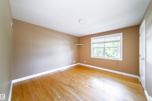 Hardwood flooring throughout, neutral tone wall paint, white trim, window with blinds, and a built-in wall shelf - 115 Griesbach Road Nw, Edmonton, AB - Indoor Photo Showing Other Room