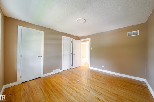 Hardwood flooring throughout, neutral wall paint, white trim, and white doors - 115 Griesbach Road Nw, Edmonton, AB - Indoor Photo Showing Other Room