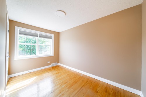 Hardwood flooring, neutral wall color, white trim, window with blinds, and flush mount lighting - 115 Griesbach Road Nw, Edmonton, AB - Indoor Photo Showing Other Room