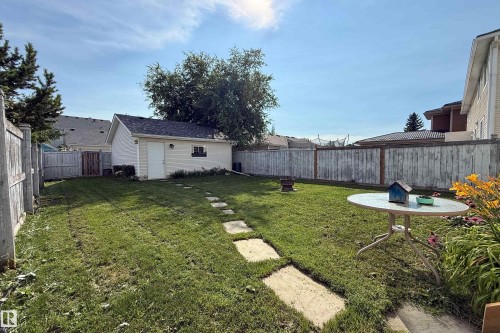 Expansive fenced backyard featuring a detached garage, established lawn, and stone pathway - 115 Griesbach Road Nw, Edmonton, AB - Outdoor With Backyard