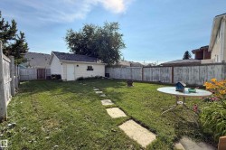 Expansive fenced backyard featuring a detached garage, established lawn, and stone pathway - 