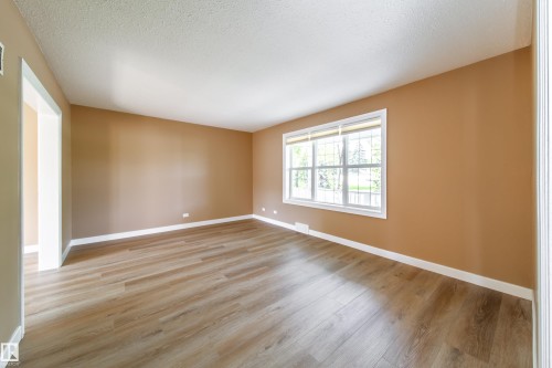 Wood-finish plank flooring, neutral wall tones, white trim, and a large window with white framing - 115 Griesbach Road Nw, Edmonton, AB - Indoor Photo Showing Other Room