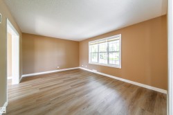 Wood-finish plank flooring, neutral wall tones, white trim, and a large window with white framing - 