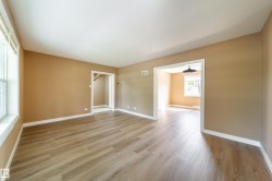 Spacious room with wood-finish flooring, neutral wall tones, and white trim - 