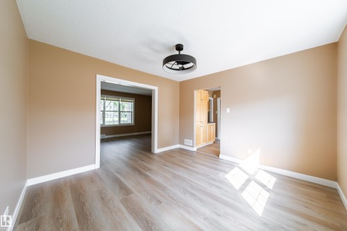Light wood-finish flooring, neutral wall paint, white trim, and a contemporary ceiling fixture - 115 Griesbach Road Nw, Edmonton, AB - Indoor Photo Showing Other Room