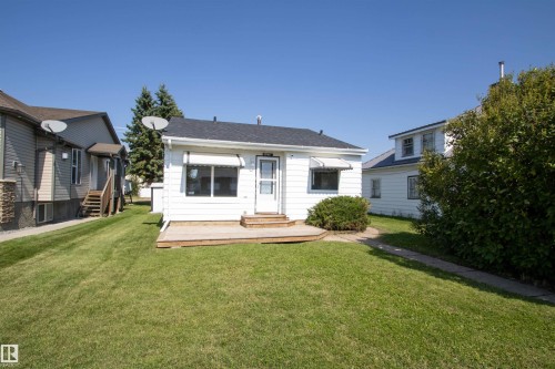 White exterior with a dark shingle roof, a front door, and a wood deck - 4706 51 Ave, St. Paul Town, AB - Outdoor