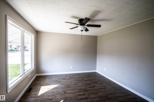 Recessed ceiling panels, dark wood-finish flooring, and a ceiling fan with integrated lighting - 4706 51 Ave, St. Paul Town, AB - Indoor Photo Showing Other Room