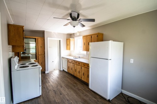 Kitchen with wood-finish flooring, wood cabinetry, white countertops, and a tile backsplash - 4706 51 Ave, St. Paul Town, AB - Indoor Photo Showing Kitchen