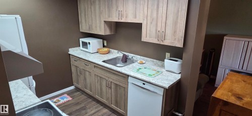 Kitchenette featuring wood-finish cabinetry, light-toned countertops, and an undermount sink - #215 4404 122 St Nw, Edmonton, AB - Indoor Photo Showing Kitchen