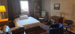 Room featuring wood-finish flooring, a built-in bookshelf, and a window with dark drapery - 