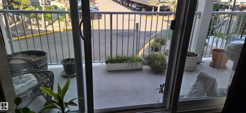 Sliding glass doors opening to an exterior balcony with metal railings and a concrete surface - #215 4404 122 St Nw, Edmonton, AB - Outdoor With Exterior