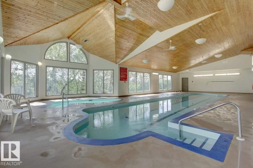 Indoor swimming pool with integrated hot tub, wood-panel vaulted ceiling, extensive window-wall, and recessed lighting - #215 4404 122 St Nw, Edmonton, AB - Indoor Photo Showing Other Room With In Ground Pool