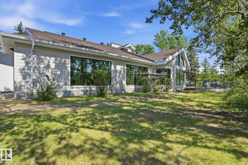 Siding exterior with multiple large windows, an arched window, and a ground-level deck with a railing - #215 4404 122 St Nw, Edmonton, AB - Outdoor