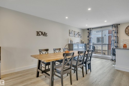 Recessed lighting, wood-finish flooring, a sliding glass door, and a built-in kitchen island - #4 9250 156 Av Nw, Edmonton, AB - Indoor Photo Showing Dining Room