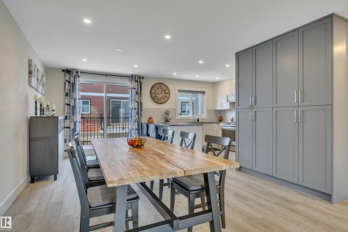 Open-concept living space with light wood-finish flooring, recessed lighting, a sliding glass door, and extensive gray cabinetry - #4 9250 156 Av Nw, Edmonton, AB - Indoor Photo Showing Dining Room