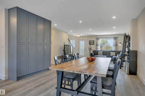 Built-in cabinetry with modern hardware, recessed lighting, wood-finish flooring, and a large window - #4 9250 156 Av Nw, Edmonton, AB - Indoor Photo Showing Dining Room