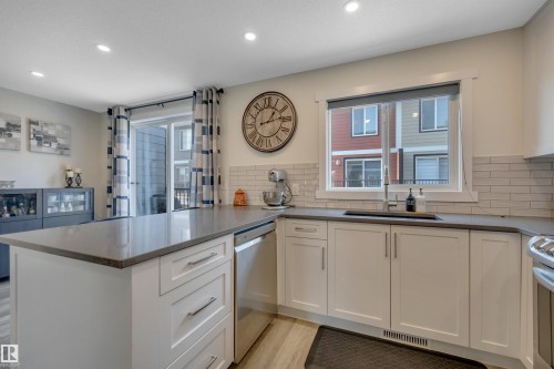 Kitchen featuring recessed lighting, white cabinetry, a built-in dishwasher, a single basin sink with a gooseneck faucet, and light wood-finish flooring - #4 9250 156 Av Nw, Edmonton, AB - Indoor Photo Showing Kitchen