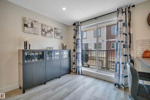 Recessed lighting, wood-finish flooring, and a sliding glass door to an exterior balcony - #4 9250 156 Av Nw, Edmonton, AB - Indoor Photo Showing Other Room