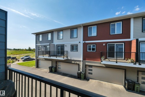 Multi-level townhome featuring a private balcony with black railings, a two-car garage, and two-tone exterior siding - #4 9250 156 Av Nw, Edmonton, AB - Outdoor