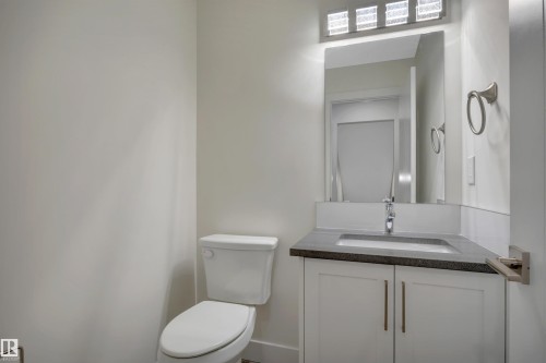 White shaker-style vanity with metal pulls, dark countertop, rectangular undermount sink, and chrome faucet - #4 9250 156 Av Nw, Edmonton, AB - Indoor Photo Showing Bathroom