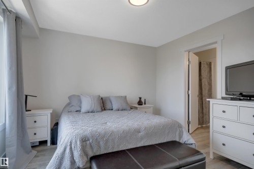 Recessed ceiling light fixture, light gray wall paint, wood-finish flooring, white trim work, and a paneled interior door - #4 9250 156 Av Nw, Edmonton, AB - Indoor Photo Showing Bedroom