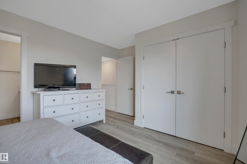 Wood-finish flooring throughout, white interior doors with brushed nickel hardware, and neutral wall tones - #4 9250 156 Av Nw, Edmonton, AB - Indoor Photo Showing Bedroom