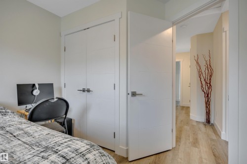 Light-toned walls complement the wood-finish flooring - #4 9250 156 Av Nw, Edmonton, AB - Indoor Photo Showing Bedroom
