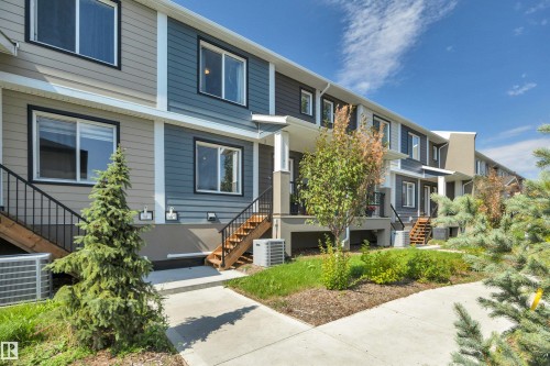 Contemporary townhome with multi-tone siding, contrasting trim, and mature landscaping - #4 9250 156 Av Nw, Edmonton, AB - Outdoor With Facade