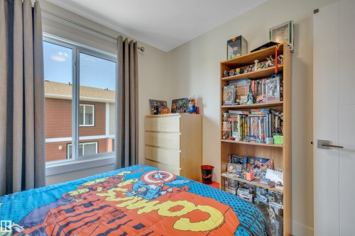 Window with light-toned curtains, a light wood-finish chest of drawers, and a built-in wood-finish bookshelf - #4 9250 156 Av Nw, Edmonton, AB - Indoor Photo Showing Bedroom