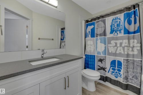 Vanity with integrated sink, polished chrome faucet, gray countertop, and light wood-finish flooring - #4 9250 156 Av Nw, Edmonton, AB - Indoor Photo Showing Bathroom