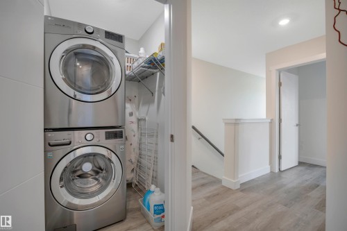 Dedicated laundry area with stacked stainless steel appliances and wire shelving - #4 9250 156 Av Nw, Edmonton, AB - Indoor Photo Showing Laundry Room