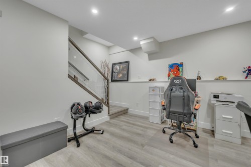 Wood-finish flooring with recessed lighting, a staircase featuring a glass railing, and neutral wall paint - #4 9250 156 Av Nw, Edmonton, AB - Indoor Photo Showing Other Room