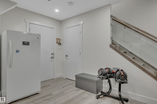Light wood-finish flooring, recessed ceiling lighting, and a modern glass and wood-finish staircase railing - #4 9250 156 Av Nw, Edmonton, AB - Indoor Photo Showing Other Room