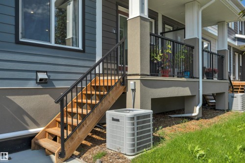 Exterior featuring horizontal siding, a stucco foundation, and a wood staircase with black metal railings - #4 9250 156 Av Nw, Edmonton, AB - Outdoor