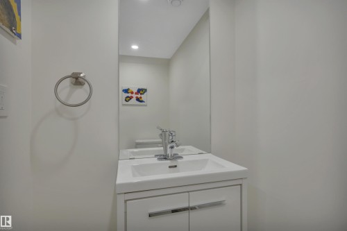 White vanity with integrated sink, chrome faucet, full-height mirror, and recessed lighting - #4 9250 156 Av Nw, Edmonton, AB - Indoor Photo Showing Bathroom