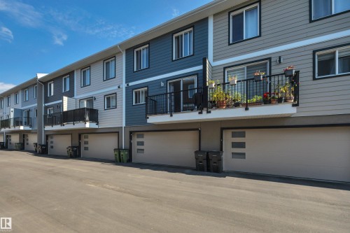 Multi-level townhome exterior featuring contemporary siding, private balconies with black railings, and integrated garages with modern accent windows - #4 9250 156 Av Nw, Edmonton, AB - Outdoor