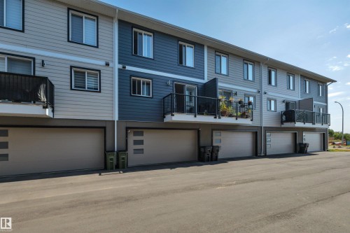 Multi-story residences featuring horizontal siding, individual balconies with black metal railings, and integrated ground-level garages - #4 9250 156 Av Nw, Edmonton, AB - Outdoor