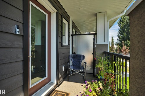 Covered balcony featuring dark exterior siding, white trim, and black railings - #4 9250 156 Av Nw, Edmonton, AB - Outdoor With Exterior