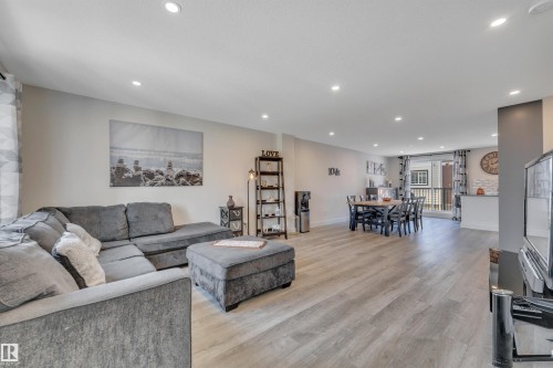 Recessed lighting illuminates the open-concept living space, featuring wood-finish flooring and light-toned walls - #4 9250 156 Av Nw, Edmonton, AB - Indoor Photo Showing Living Room