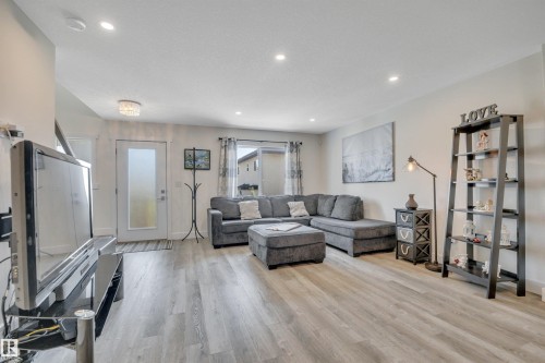 Recessed ceiling lighting, wood-finish flooring, white walls, and a frosted glass door - #4 9250 156 Av Nw, Edmonton, AB - Indoor Photo Showing Living Room