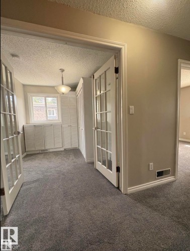 Interior room with French doors and textured grey carpeting - 11 Greenfield Estates, St. Albert, AB - Indoor Photo Showing Other Room