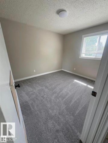 Interior room featuring neutral wall paint, gray carpeting, white baseboards, a white-framed window with blinds, and a flush-mount ceiling light fixture - 11 Greenfield Estates, St. Albert, AB - Indoor Photo Showing Other Room